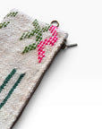 Eine Nahaufnahme einer strukturierten weißen LEY! Tasche - Colorful Line - 15 x 20, mit grünem und rosa gesticktem Muster, Reißverschluss und kleinem Metallring - ideal als vielseitige Clutch.