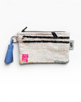 Die LEY! Tasche - Colorful Line - 15 x 20 ist eine kleine gewebte Multifunktionstasche mit Reißverschluss, abstrakten schwarzen, rosa und grünen Nähten, einer blauen Quaste und einem weißen "LEY!"-Anhänger an der Seite.