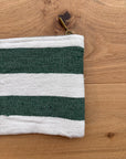 Eine grün-weiße LEY! Tasche - Stripe Line "Tilosa" (20x30cm) aus Baumwolle mit Messing-Reißverschluss liegt auf Holz, nur der obere linke Teil dieser handgefertigten Marrakesch-Tasche ist sichtbar.