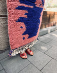 Eine Person steht auf dem Berber-Teppich „THE DANISH GIRL INTERIOR – Farah“ (0,60 x 1,10 m); ihre Füße in roten Sandalen sind zu sehen.