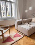 Modernes Wohnzimmer mit einem beigen Sofa, einem Holzstuhl und dem Berber-Teppich „Tazita“ von THE DANISH GIRL INTERIOR.