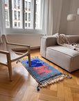 Ein Berber-Teppich aus dem Film „The Danish Girl“ – „Amani“ liegt auf einem Holzboden neben einem beigen Sessel und einem Sofa.