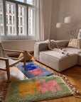 Das gemütliche Wohnzimmer mit einem beigen Sofa, einem modernen Sessel und zwei „Bariq“-Teppichen von THE DANISH GIRL INTERIOR sorgt für lebendige Farbakzente.