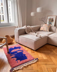 Beiges Sofa mit gemusterten Kissen, Berber-Teppich – „Farah“ von THE DANISH GIRL INTERIOR, Lampe und Kunstwerke in einem hellen Raum.