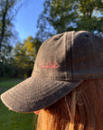 Eine Person trägt die LEY! „Habibi“-Kappe in Rosa mit verstellbarem Verschluss im Freien zwischen Bäumen und im Sonnenlicht.