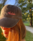Eine Person mit langen Haaren trägt die LEY! „Habibi“-Kappe in Rosa und steht draußen im Sonnenlicht.