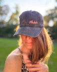 Eine Frau im Freien mit einer rosa LEY! „Habibi“-Kappe mit verstellbarem Riemen, im Hintergrund Sonnenlicht und Bäume.