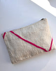 Die cremefarbene, strukturierte Tasche - Mina - 20X30 von LEY! aus Schurwolle hat leuchtend rosa Diagonalstreifen und ist in liebevoller Handarbeit gefertigt. Abgebildet ist sie auf einer weißen Fläche mit einem Schatten in der rechten oberen Ecke.