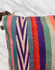 Nahaufnahme von LEY! TASCHE, einer farbenfrohen Clutch aus gewebtem Stoff mit vertikalen Streifen in Petrol, Pink, Rot, Orange, Lila und Creme. Mit Chevron-Muster und braunem Reißverschluss.