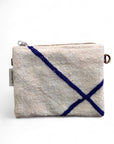 Die LEY! Tasche - Classic Line - 15x20cm ist eine rechteckige, strukturierte beige Schurwolle-Tasche mit einem Reißverschluss, zwei dunkelblauen diagonalen Linien auf der Vorderseite, einem kleinen Stoffanhänger auf der linken Seite und einem Metallring auf der rechten Seite.