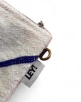 Nahaufnahme der LEY! Tasche - Classic Line - 15x20cm: eine Stofftasche mit Reißverschluss, Metallring, blauem Streifendetail und weißem "LEY!"-Tag-Schurwolle-Design, inspiriert von Handarbeit Marrakesch auf weißem Hintergrund.