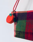 Eine bunt karierte Tasche mit einem LEY! Schlüsselanhänger - Etui - Orange und einem rot-grünen Münzbeutel am Gurt.