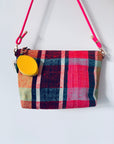 Eine bunt karierte Handtasche mit glattem Reißverschluss bietet der LEY! Schlüsselanhänger - Zitrone und hängt an einem leuchtend pinken Band vor einem schlichten weißen Hintergrund.