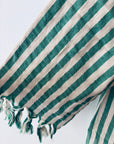 Eine Nahaufnahme des KIMONO - MEDITERANE - GRÜN - WEIß von THE DANISH GIRL INTERIOR zeigt grüne und weiße vertikale Streifen auf einem strukturierten, weichen Stoff mit ausgefransten Kanten und einigen losen Fäden am unteren Rand.