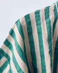 Eine Nahaufnahme des KIMONO - MEDITERANE - GRÜN - WEIß von THE DANISH GIRL INTERIOR zeigt seine vertikalen grünen und weißen Streifen mit sichtbarer Textur und Falten, drapiert vor einem hellen Hintergrund.