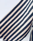 Nahaufnahme des Stoffes KIMONO - MEDITERANE - SCHWARZ - WEIß von THE DANISH GIRL INTERIOR: weich, leicht, mit vertikalen schwarzen und weißen Streifen, an einer Kante leicht gerafft. Perfekt für Mäntel oder Jacken. Abgebildet auf einfarbig weißem Grund.