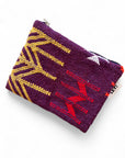 Die LEY! Tasche - Colorful Line (15x20cm) ist aus Schurwolle in Lila mit gelb-roten geometrischen Mustern, weißem Stern-Design, Reißverschluss oben und kleinem weißen Tag mit schwarzer Aufschrift. Handgefertigt in Marrakesch.