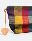 Nahaufnahme eines farbenfrohen, karierten Beutels mit dem LEY! Taschenanhänger – Love Loop – Apricot als Reißverschlussanhänger.