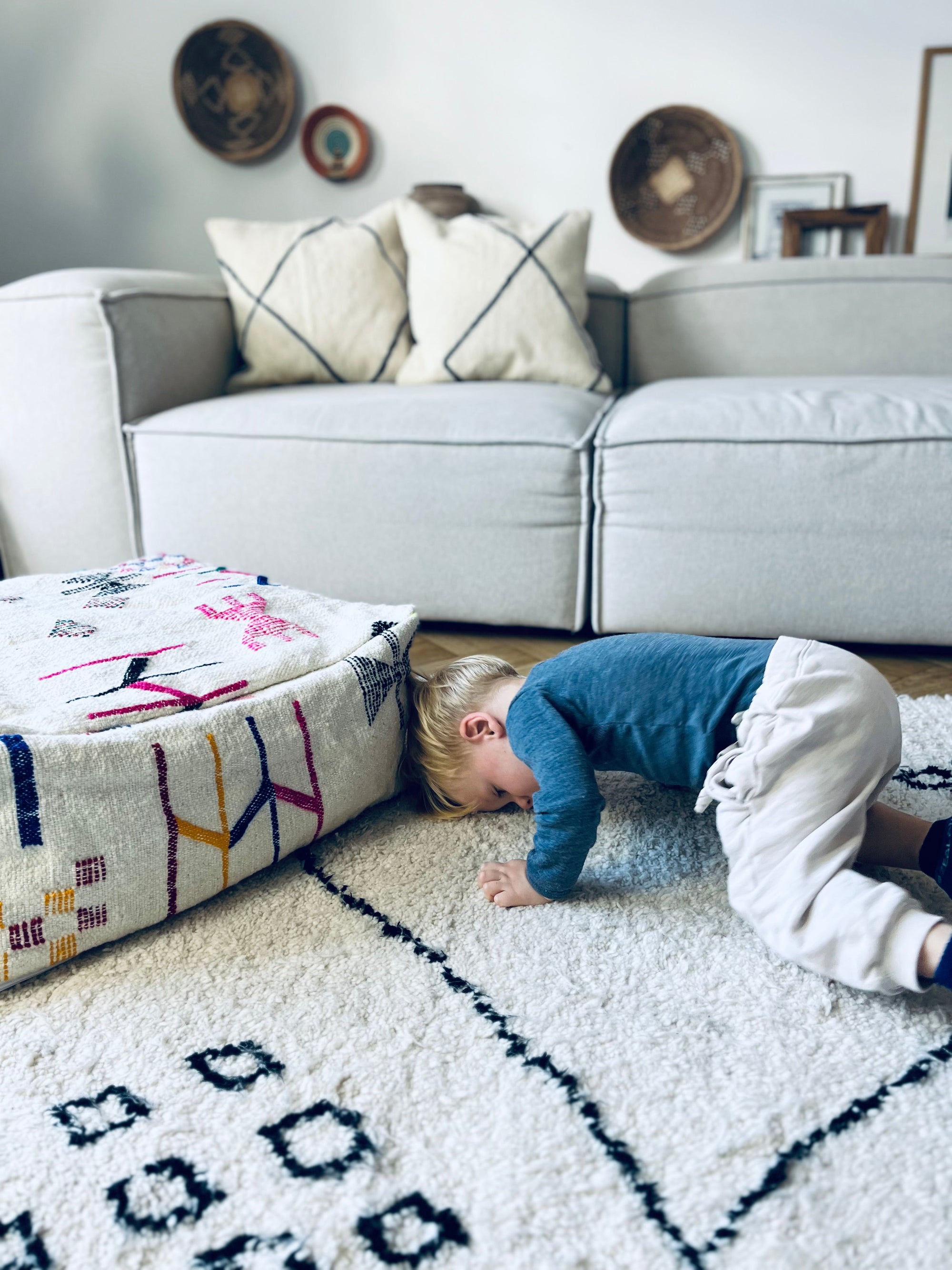 Tobendes Kind auf einem Berberteppich mit buntem Bodenkissen (perfekt fürs Kinderzimmer) auf Berberteppich.