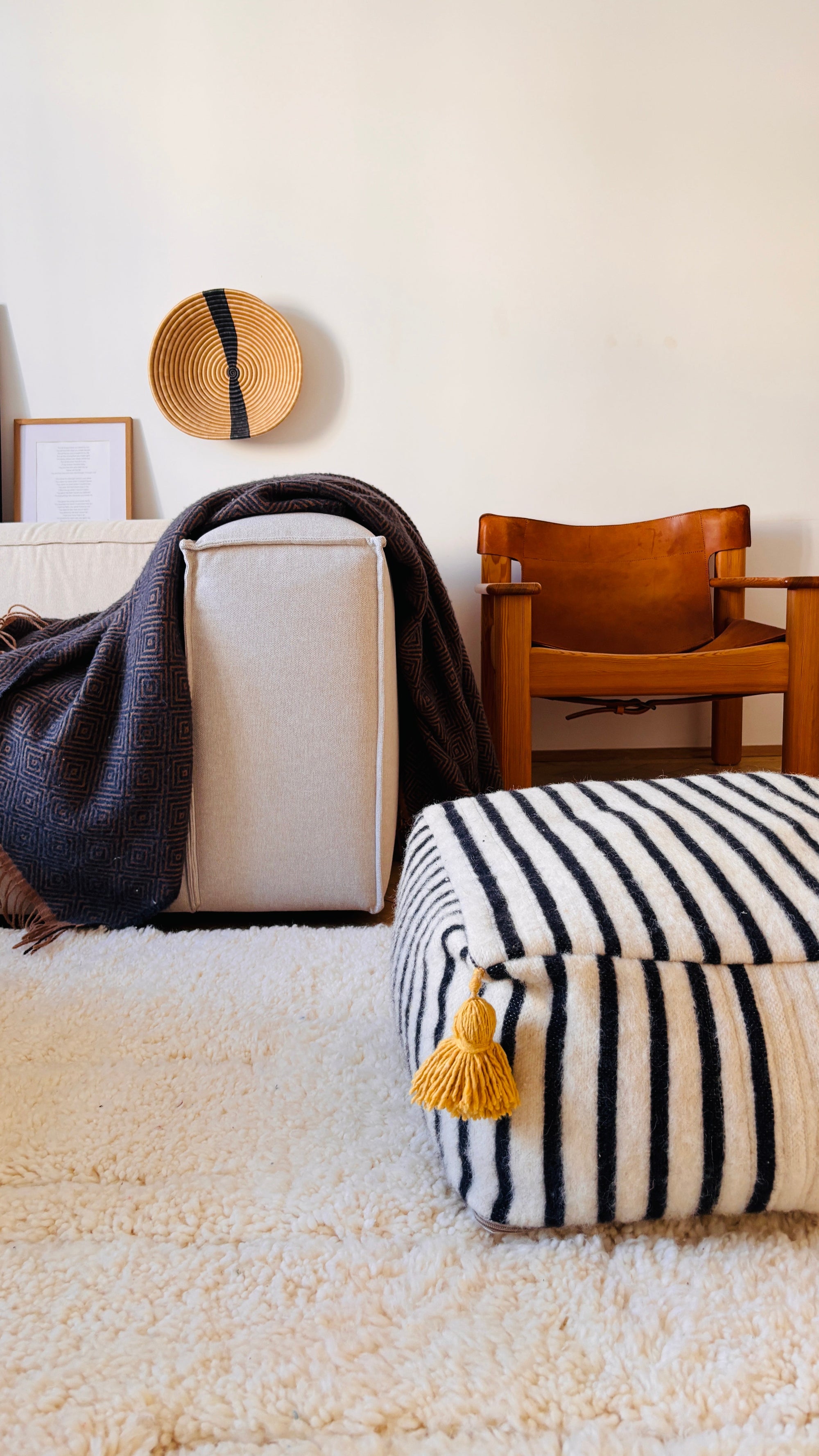 LEY Bodenkissen auf neutralem Berberteppich vor einem beigen Sofa.