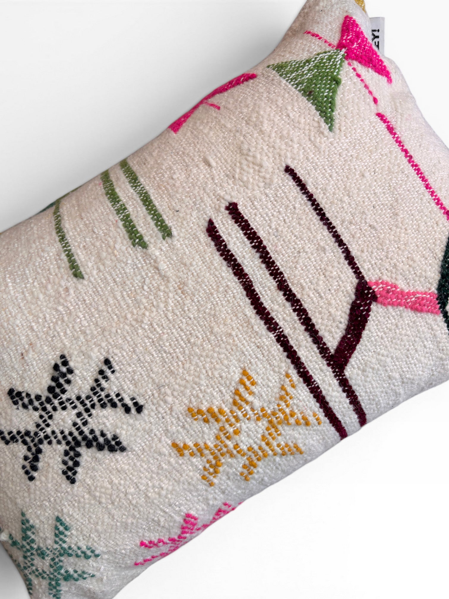 Das LEY! Kissen - Colorful Line - 40 x 60 von LEY! ist ein handgemachtes, rechteckiges, cremefarbenes Kissen mit strukturiertem Schurwolle-Stoff und geometrischen Mustern in Grün, Rosa, Gelb, Braun und Schwarz. Es ist mit einem kleinen Etikett in der rechten oberen Ecke versehen.