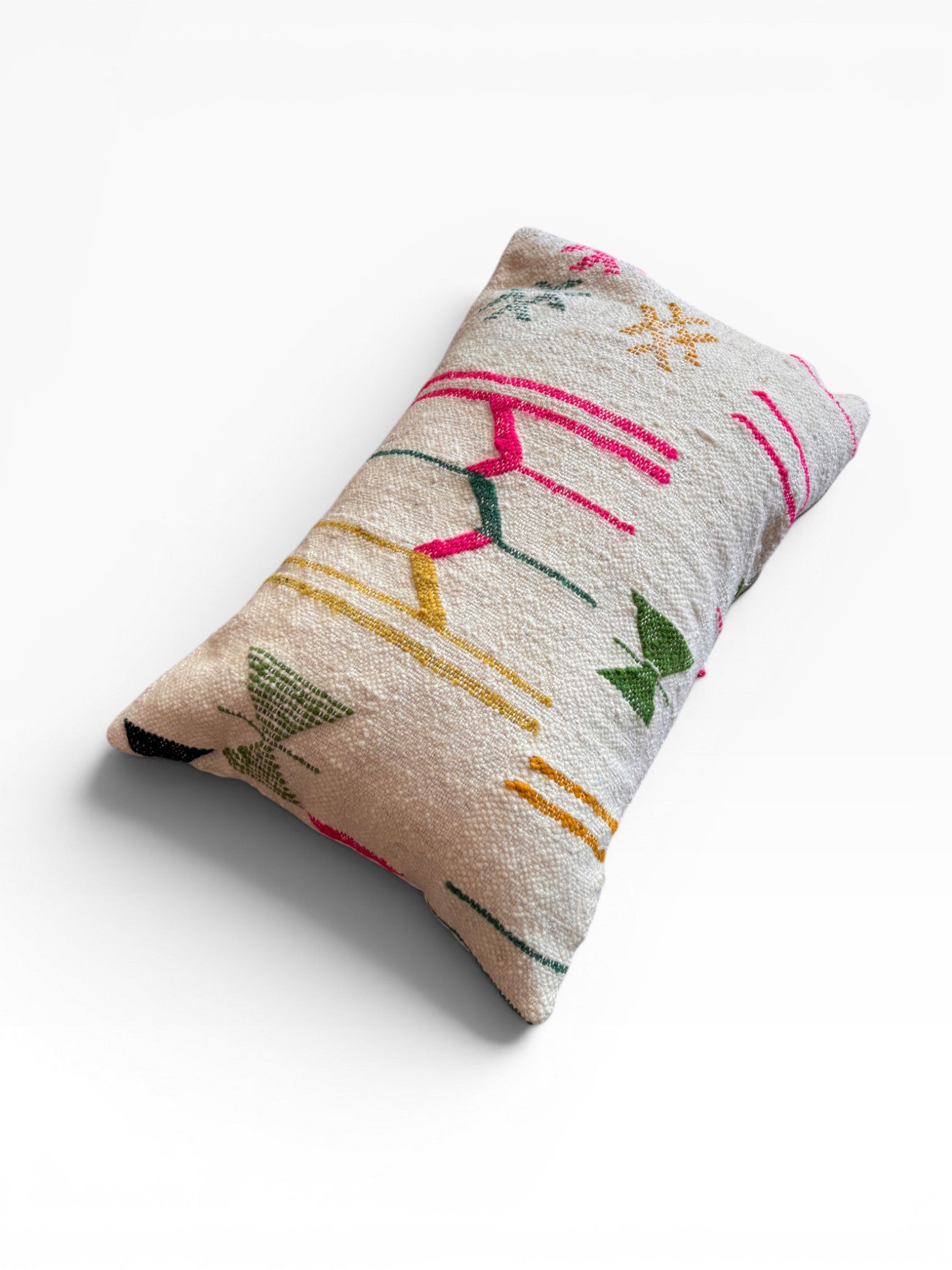 Das LEY! Kissen - Colorful Line (40x60), ein rechteckiges Kissen mit strukturiertem beigem Stoff und lebhaften geometrischen Mustern in Grün, Gelb, Rot und Schwarz von LEY!, sticht als mutiger Akzent auf einer schlichten weißen Fläche hervor.