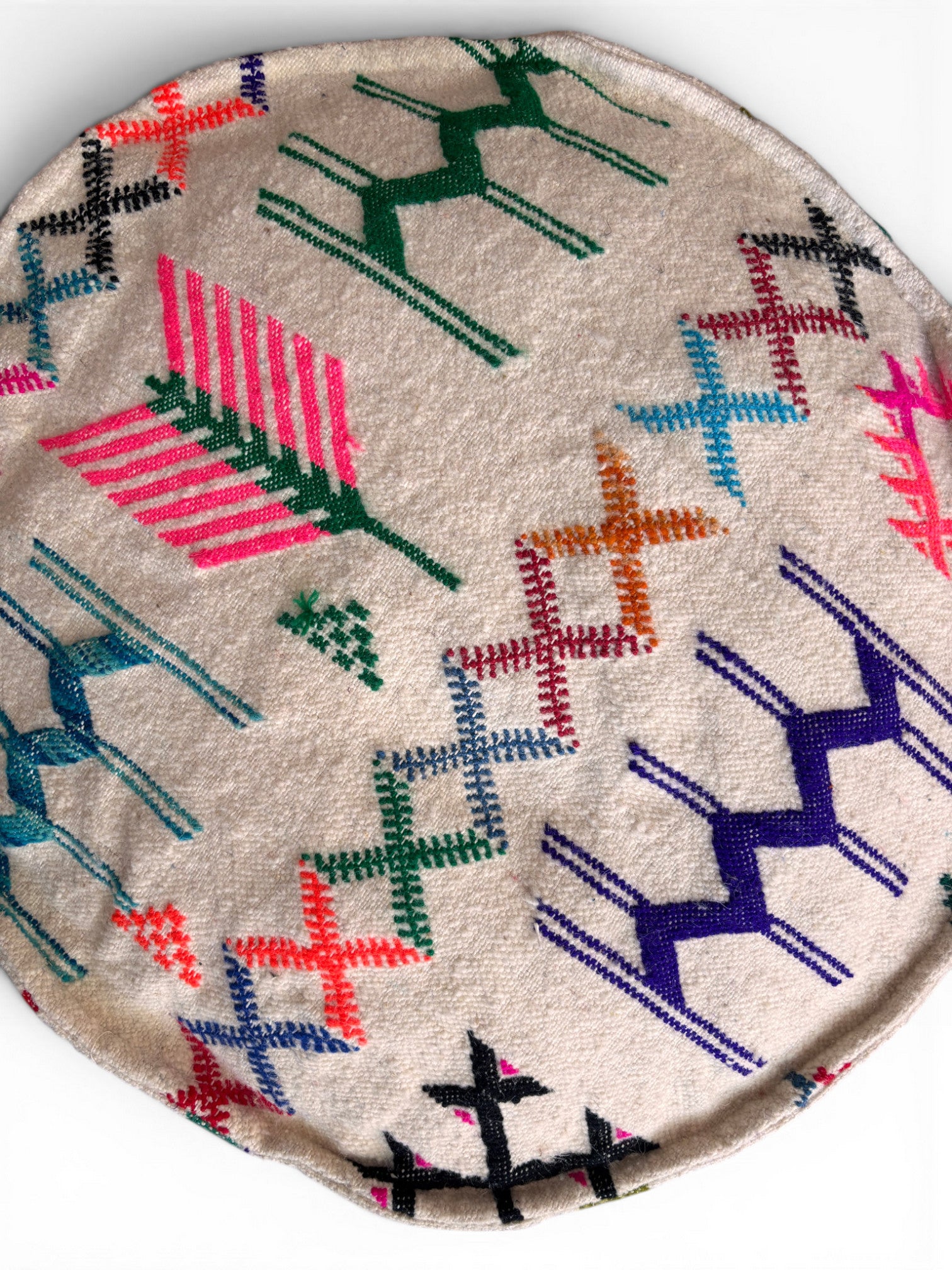 Das LEY! Bodenkissen - Colorful Line Round - Haraka ist ein beiges, rundes Boho-Bodenkissen mit lebhaften geometrischen und pfeilartigen Mustern in Rosa, Grün, Blau, Orange und Lila auf weißem Hintergrund.