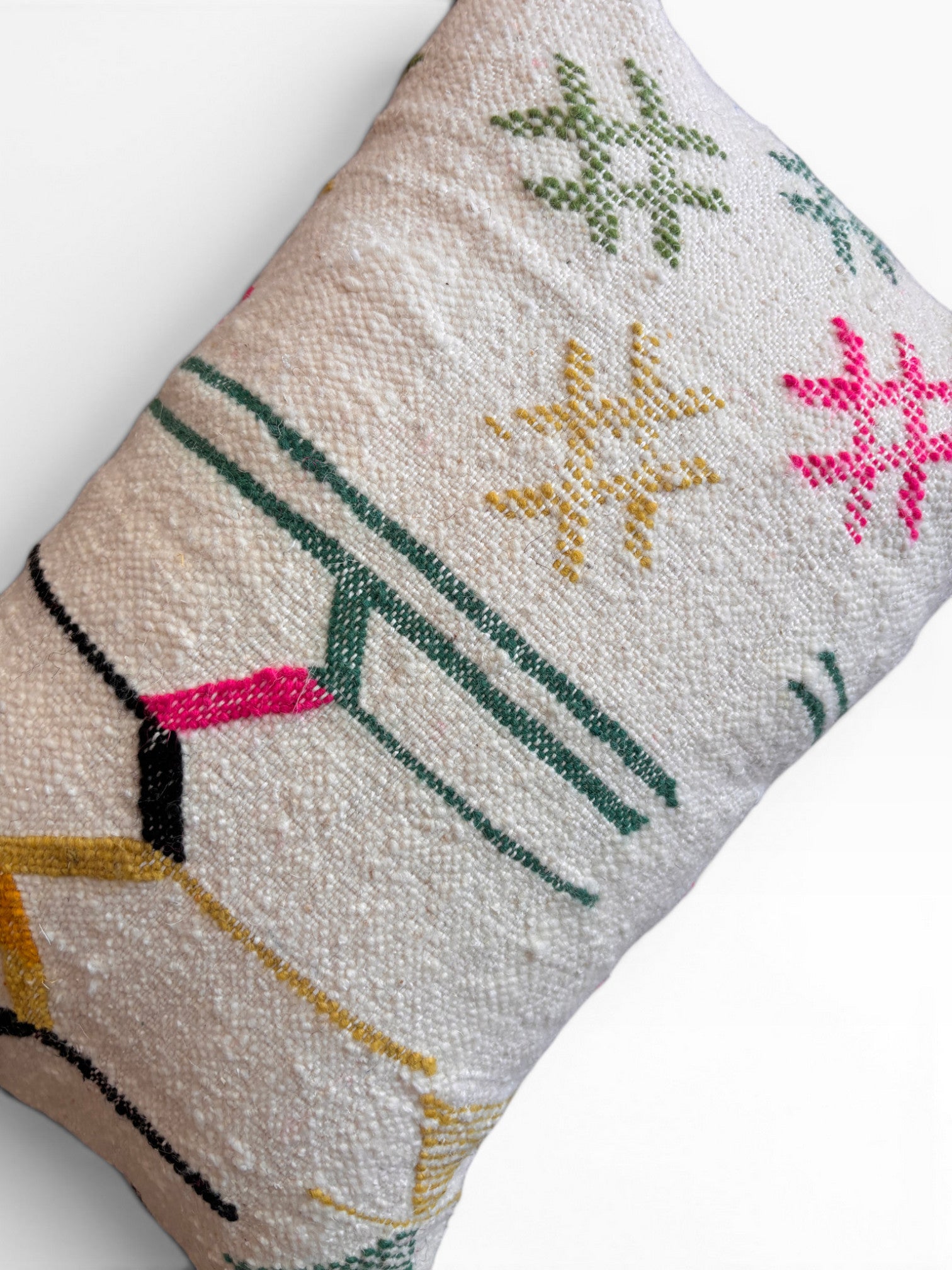 Das LEY! Kissen - Colorful Line - 40 x 60 von LEY! besteht aus strukturiertem weißem Schurwolle-Stoff mit geometrischer Stickerei in Grün, Gelb, Rosa und Schwarz, inspiriert von den markanten Linien und Sternenmotiven der Handarbeit Marrakesch.