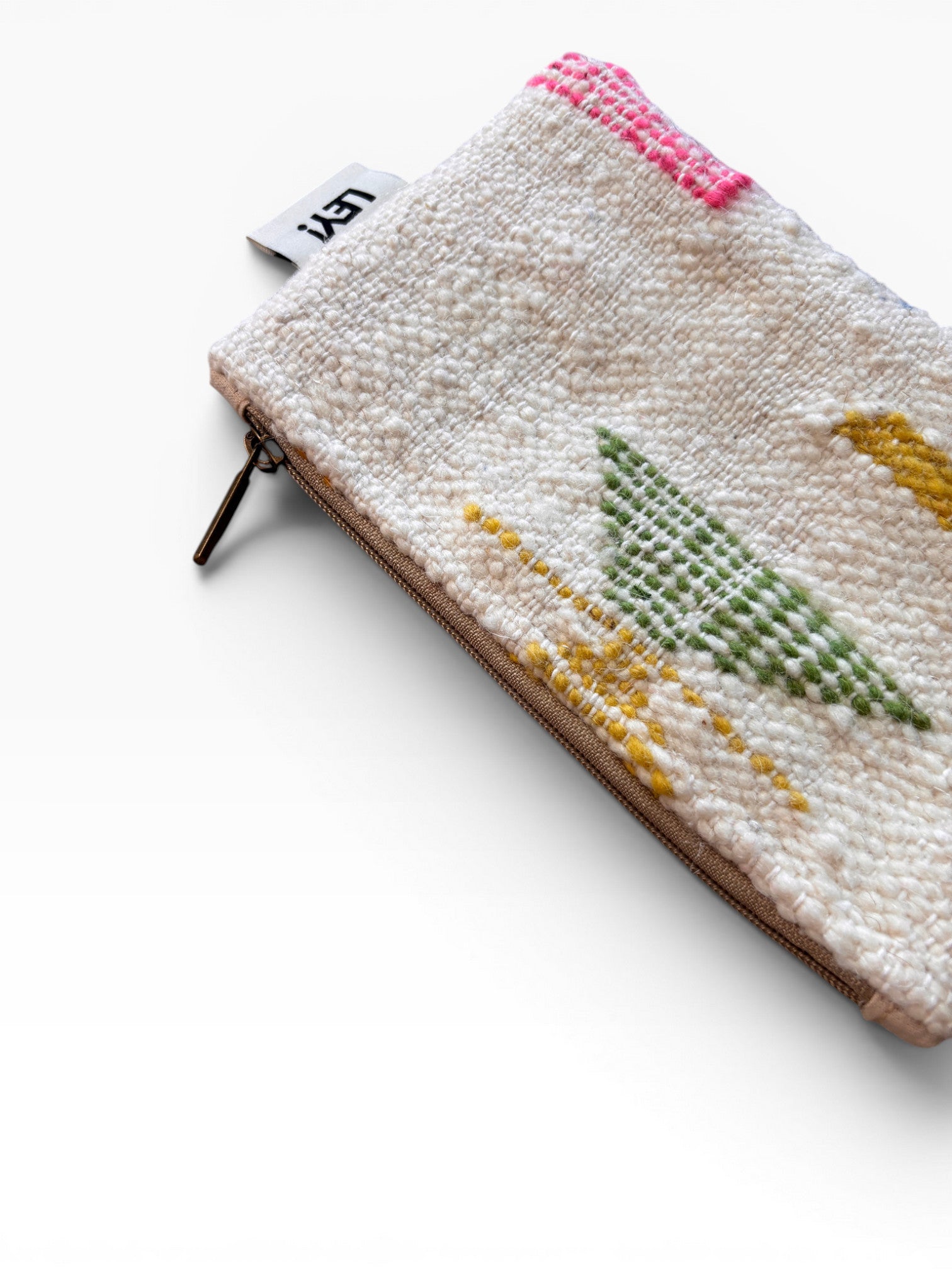 Die LEY! Tasche - Colorful Line - 15 x 20 hat ein strukturiertes Schurwolle-Design mit grünen, gelben und rosafarbenen gewebten Linien und einem weißen Etikett an der Oberseite. Diese multifunktionale Clutch steht auf einer schlichten weißen Oberfläche.