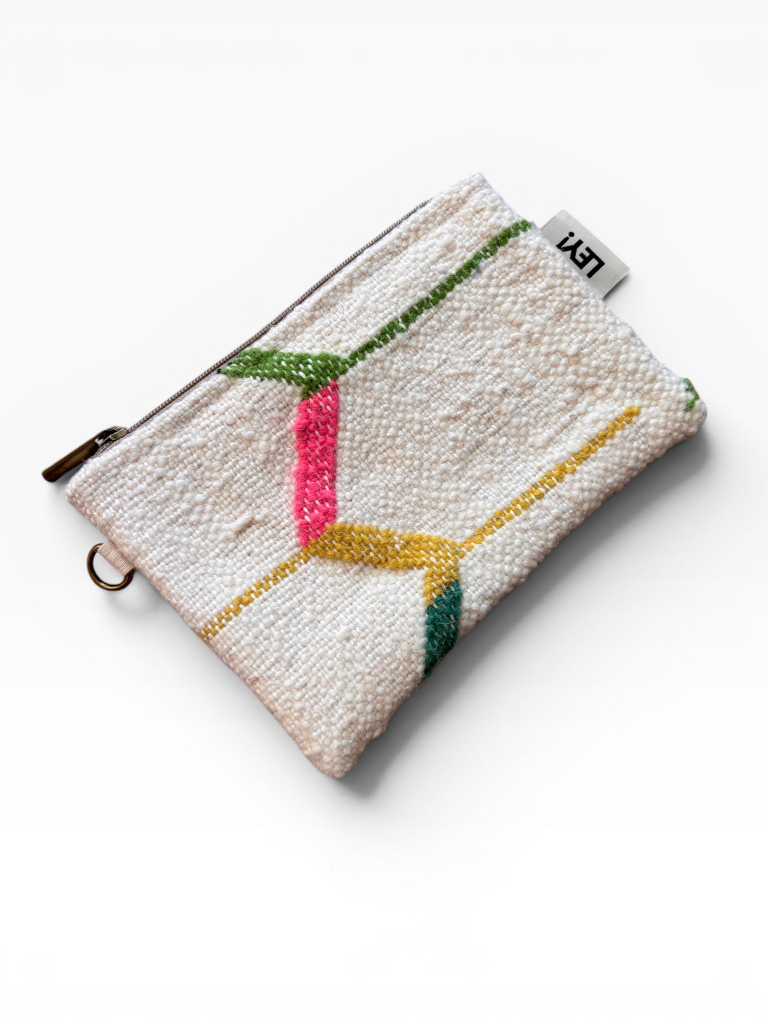 Die LEY! Tasche - Colorful Line - 15 x 20 ist eine kleine, strukturierte, cremefarbene Clutch mit Messingreißverschluss, weißem Anhänger und abstrakten, gestickten Linien in Pink, Gelb, Grün und Blau.