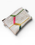 Die LEY! Tasche - Colorful Line - 15 x 20 ist eine kleine, strukturierte, cremefarbene Clutch mit Messingreißverschluss, weißem Anhänger und abstrakten, gestickten Linien in Pink, Gelb, Grün und Blau.