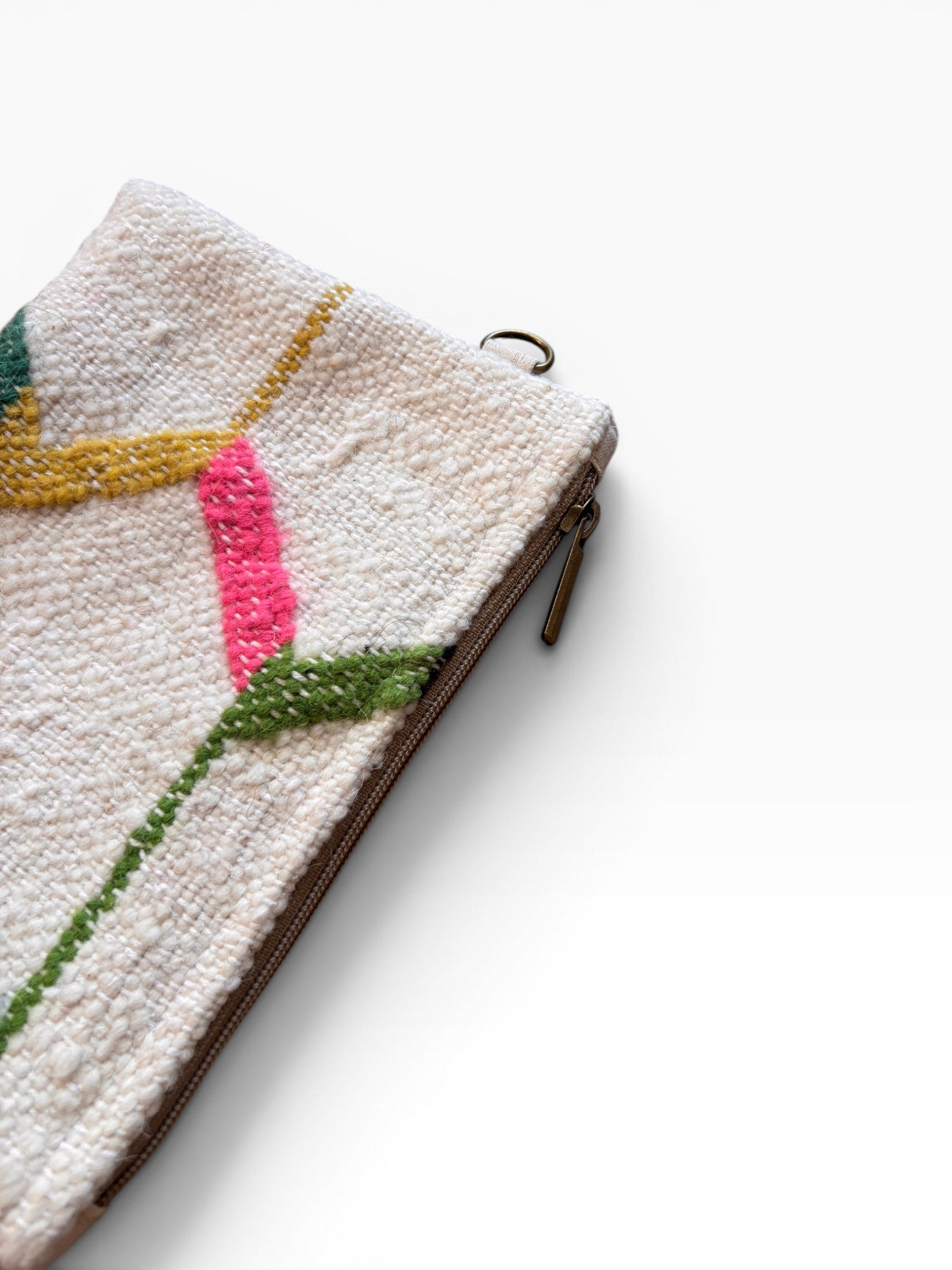 Eine Nahaufnahme der LEY! Tasche - Colorful Line - 15 x 20 Clutch, die ein strukturiertes, gewebtes Design mit einem Metallreißverschluss und lebhaften abstrakten rosa, gelben und grünen Mustern auf weißem Hintergrund aufweist.