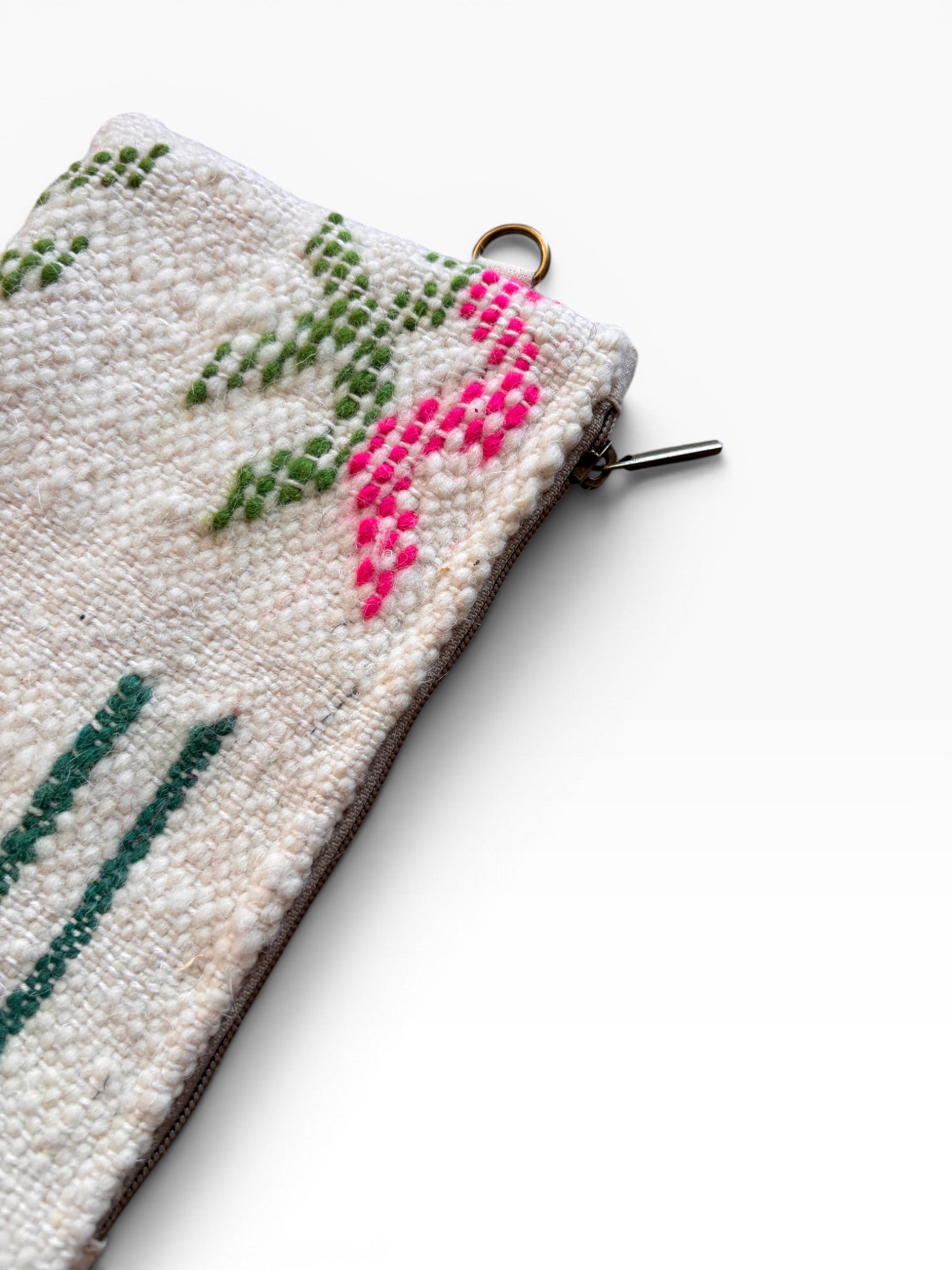 Eine Nahaufnahme einer strukturierten weißen LEY! Tasche - Colorful Line - 15 x 20, mit grünem und rosa gesticktem Muster, Reißverschluss und kleinem Metallring - ideal als vielseitige Clutch.
