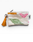 Die LEY! Tasche - Colorful Line - 15 x 20 ist eine kleine weiße Clutch mit Reißverschluss, gelber Quaste, geometrischen Mustern in Rosa, Grün und Gelb, aus strukturiertem Schurwolle-Stoff und mit einem Anhänger auf der rechten Seite.