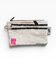 Die LEY! Tasche - Colorful Line - 15 x 20 ist eine kleine weiße Schurwolle-Tasche mit strukturiertem Stoff, schwarzem Querstreifen, rosa Quadrat, gelbem Akzent, Metallreißverschluss, multifunktionalem Clutch-Design und einem weißen Anhänger mit dem Aufdruck "LEY!" in Schwarz.
