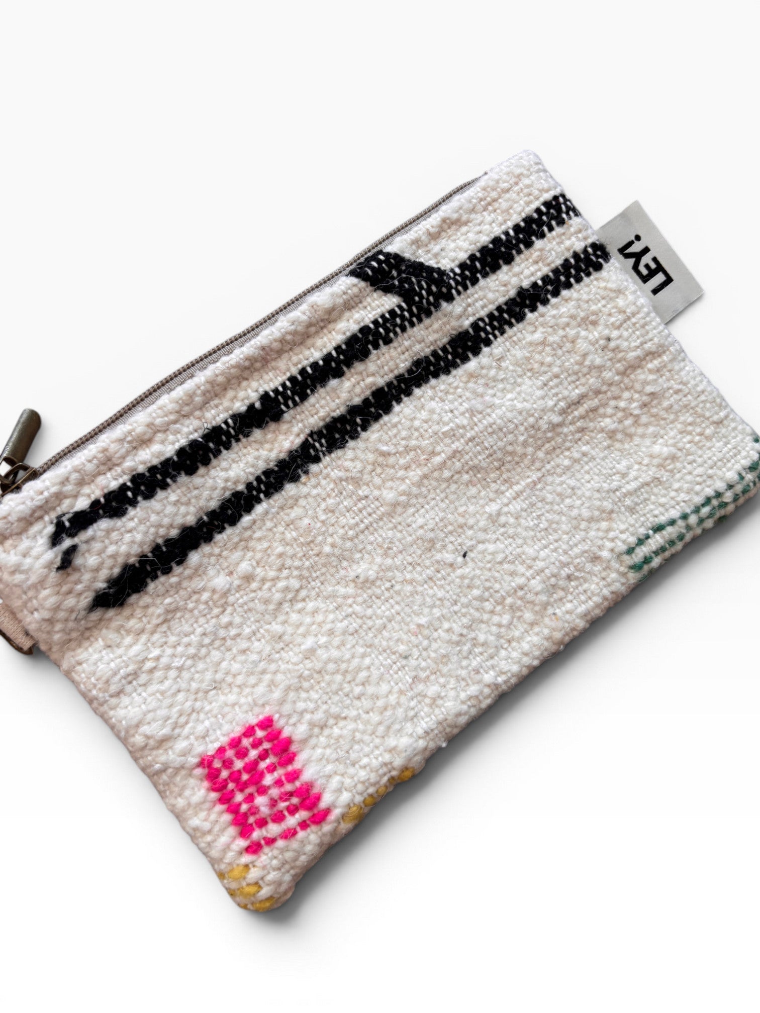 Die LEY! Tasche - Colorful Line (15 x 20) ist eine kleine gewebte Clutch mit Reißverschluss, weißem Boden, schwarzen Streifen, rosa geometrischem Muster in einer Ecke und einem seitlichen Stoffanhänger - ideal als multifunktionales Accessoire.
