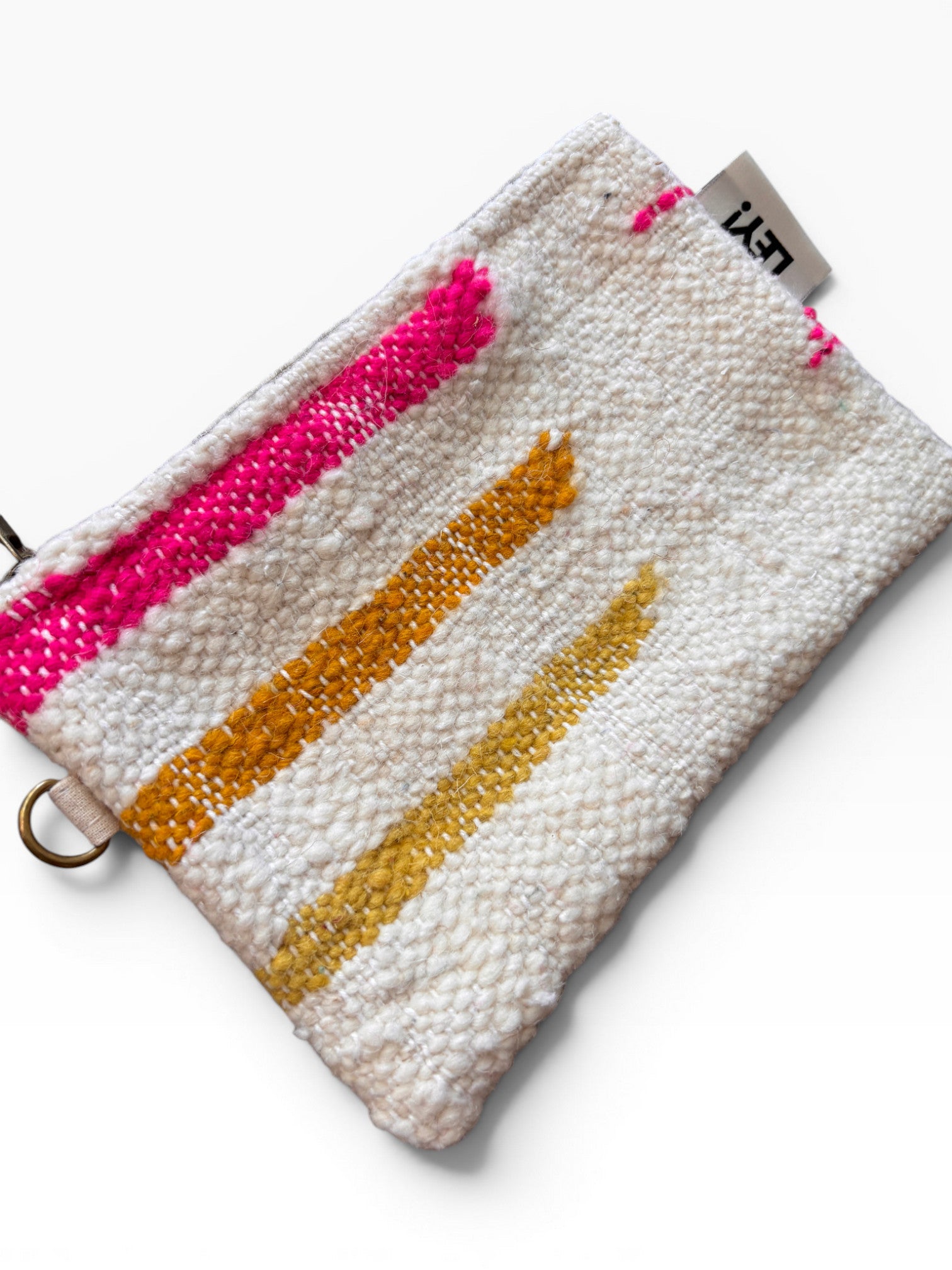 Die Tasche - Colorful Line - 15 x 20 von LEY! ist eine strukturierte weiße Reißverschlusstasche mit vertikalen rosa, orangen und gelben gewebten Streifen und einem kleinen Eckanhänger mit der Aufschrift "LEY!".