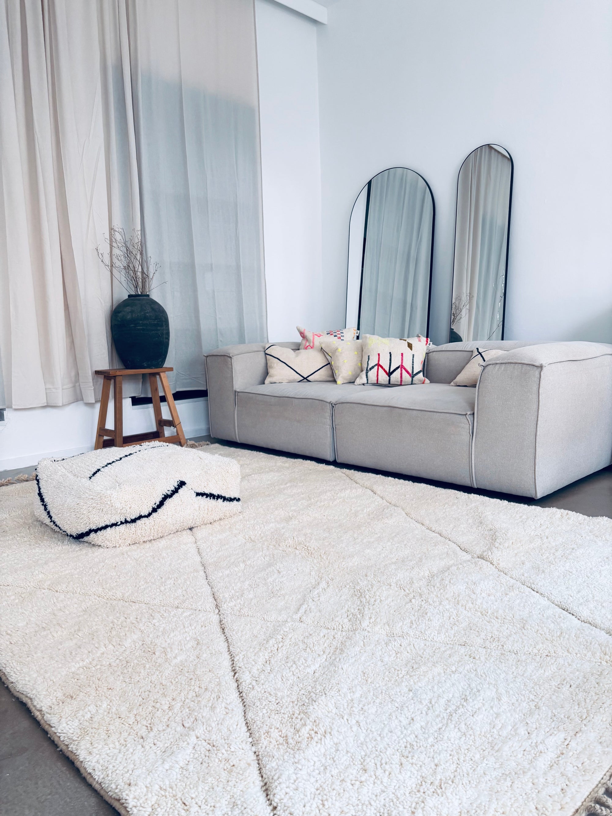 Beiger Beni Ourain Berber-Teppich im modernen Wohnraum – elegantes, schlichtes Design und weichem Pouf