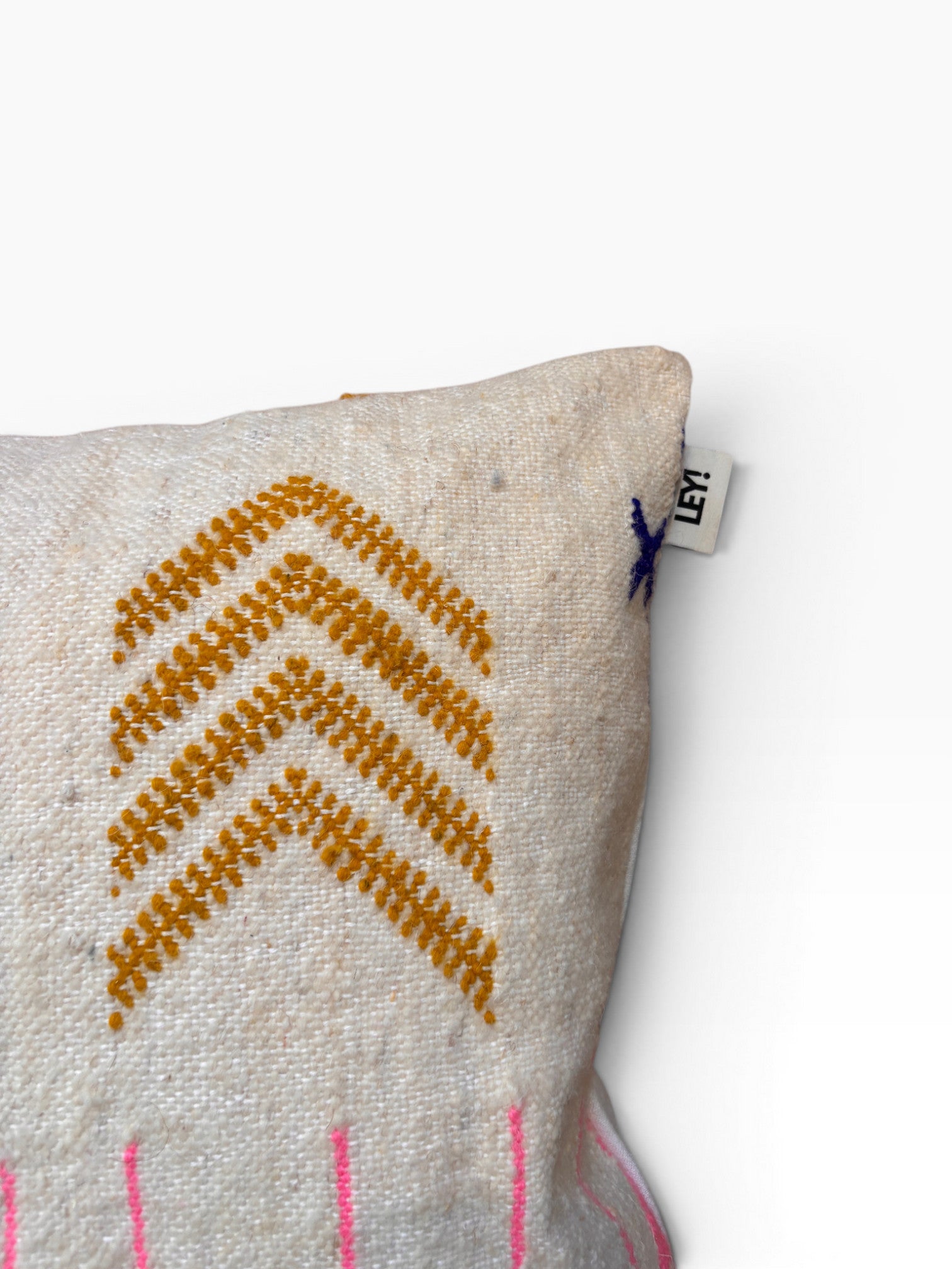 LEY! Kissen - Bunte Linie, 50x50 cm: Weißes Kissen mit gelber Chevron-Stickerei, Schild "LEY!" oben rechts.