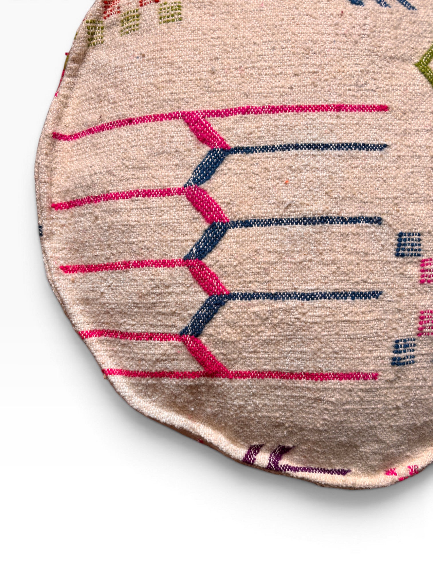 Das LEY! Bodenkissen - Colorful Line Round - Sabia ist ein beigefarbenes Bodenkissen aus Wolle mit rosa und blauen geometrischen Mustern.