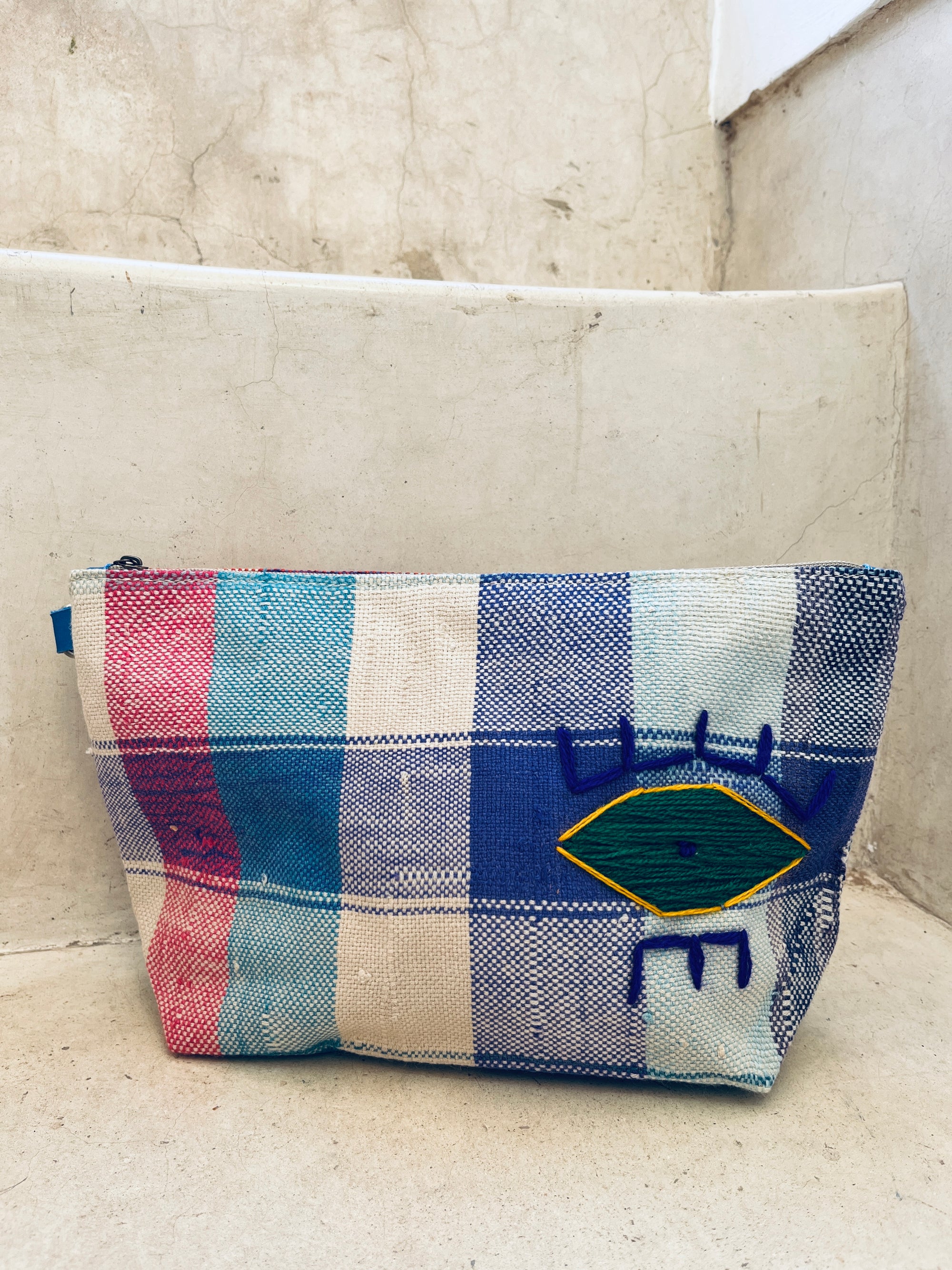 Die LEY! Kosmetiktasche beeindruckt mit blau, pink und weiß kariertem Stoff sowie gelb-grün besticktem Auge und blauen Ziernähten - ein stylischer Hingucker für deine Beauty-Essentials.