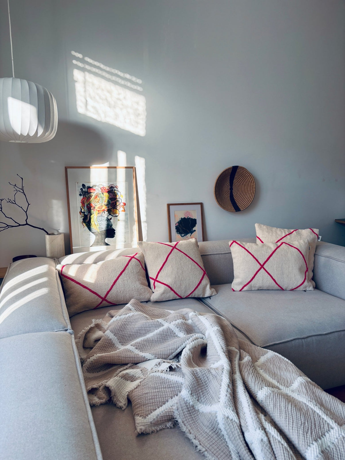 Modernes Wohnzimmer mit einem cremefarbenen Sofa, Kissen von LEY! – Classic Line Mina 30x50, gemusterten Kissen und natürlichem Licht.