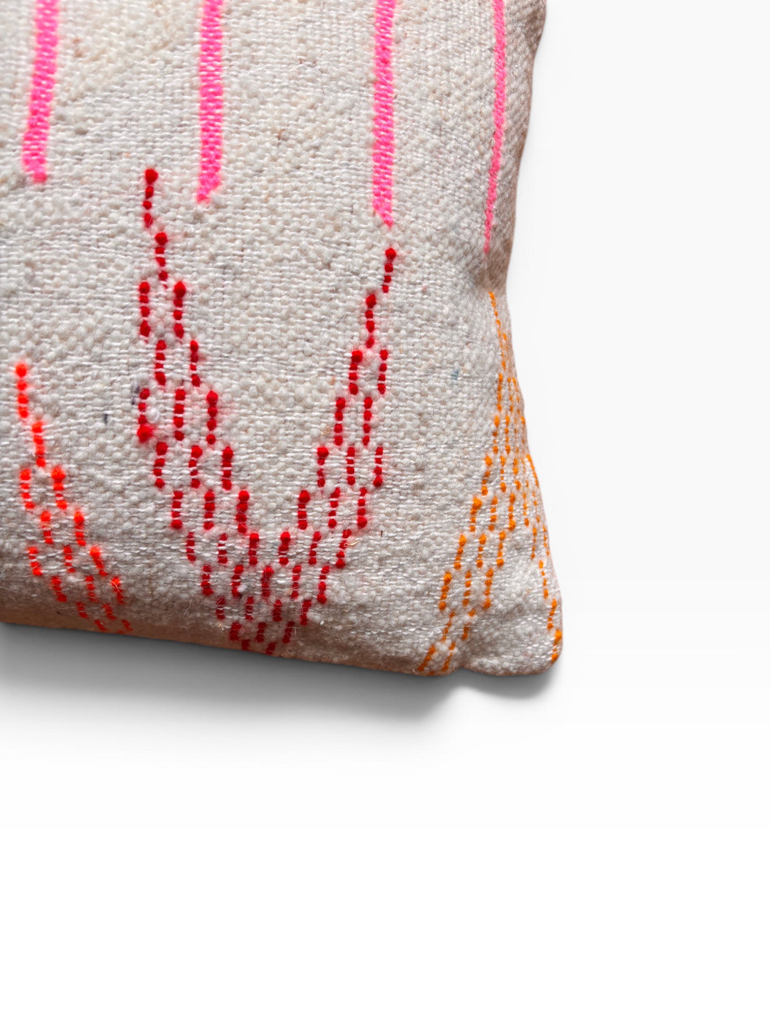 Nahaufnahme von LEY! Kissen - Colorful Line: ein weißes Schurwollkissen mit rosa, roten und orangen Nähten auf weißem Grund.