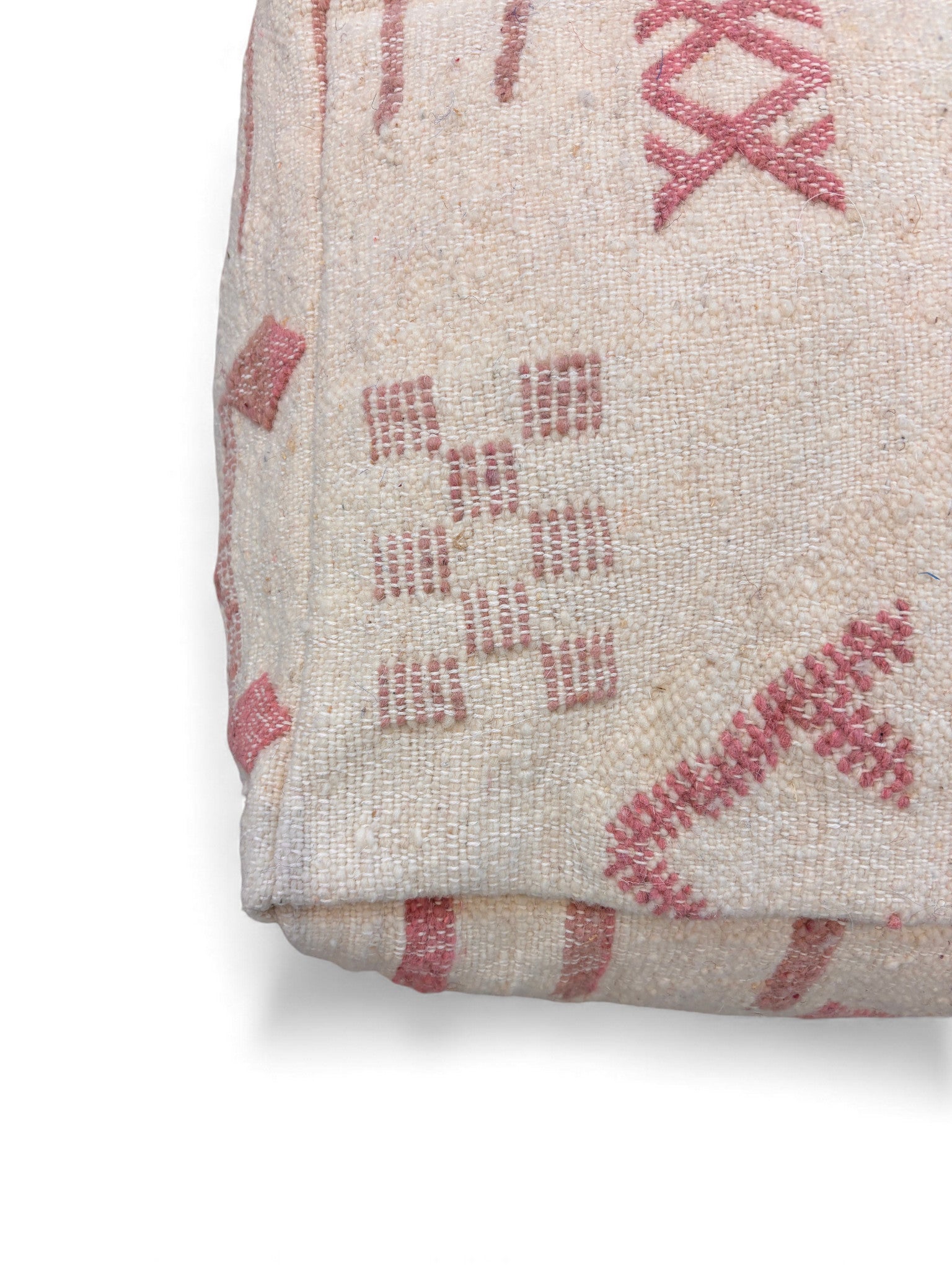Eine Nahaufnahme des LEY! Kleines Bodenkissen - Classic Line - Mila Pale, einem handgefertigten cremefarbenen Bodenkissen mit rosa geometrischen und Tribal-Motiven in feiner Schurwolle, vor weißem Hintergrund.