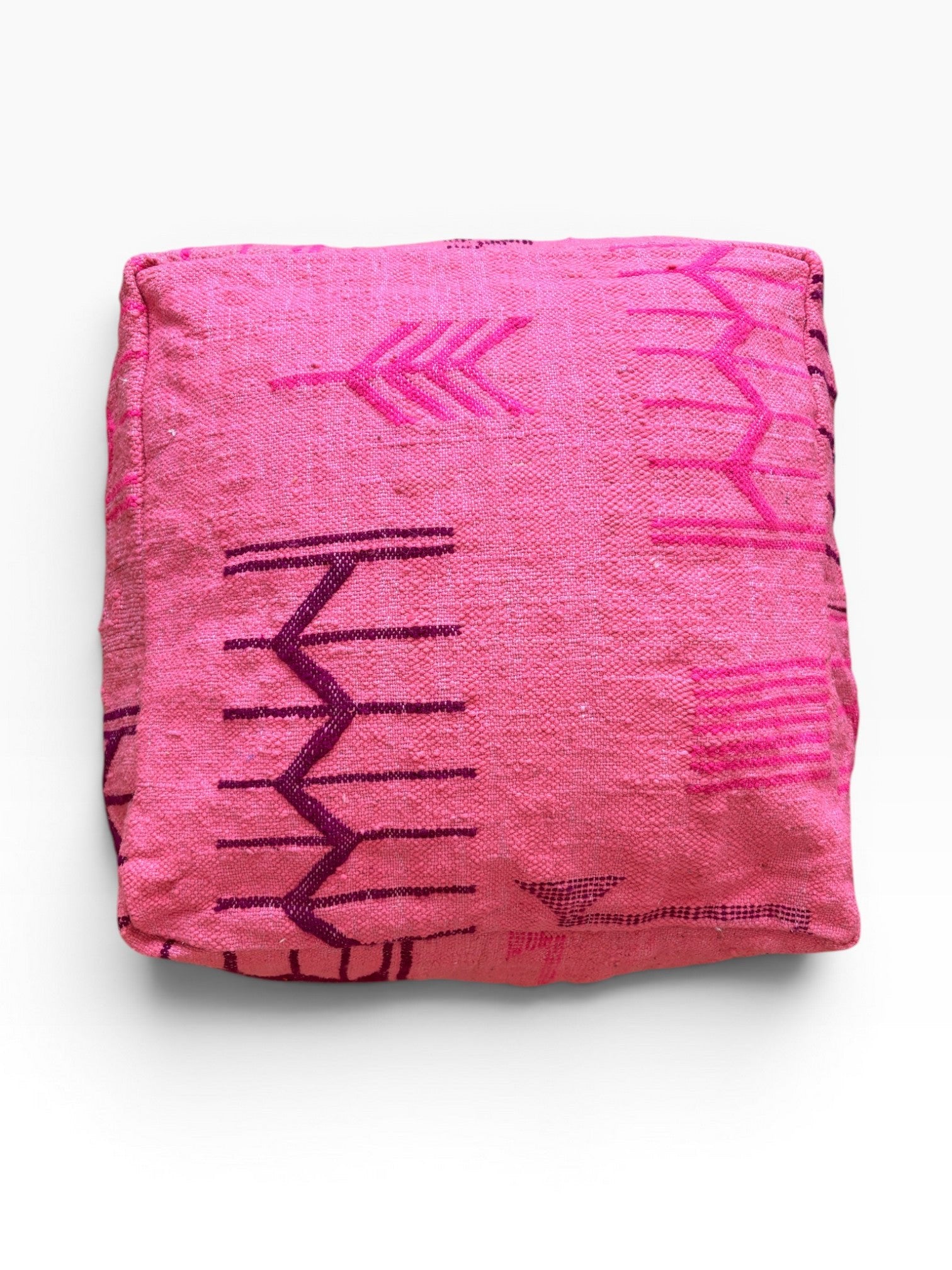 Ein gefaltetes Bodenkissen - Colorful Line - Pink Edition von LEY! mit geometrischen lila Mustern auf Schurwolle, weißem Hintergrund.