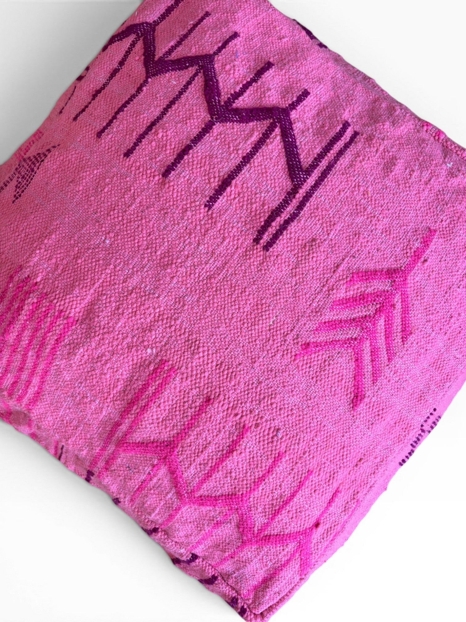 LEY! Bodenkissen - Colorful Line - Pink Edition: rosa Kissen mit lila und magentafarbenen Mustern auf weißer Schurwolle.