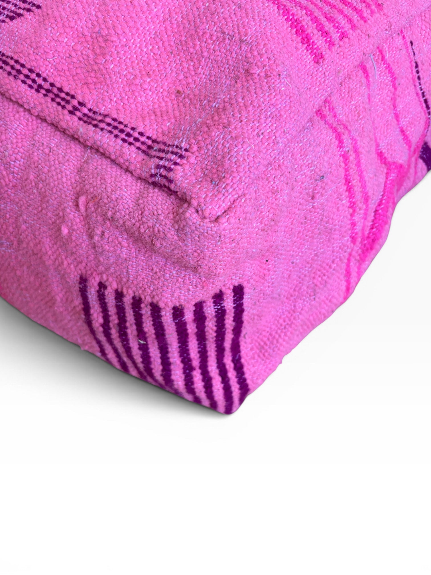 Ein gefaltetes rosa Handtuch mit lila Streifen neben einem LEY! Bodenkissen - Colorful Line - Pink Edition auf einer weißen Fläche.
