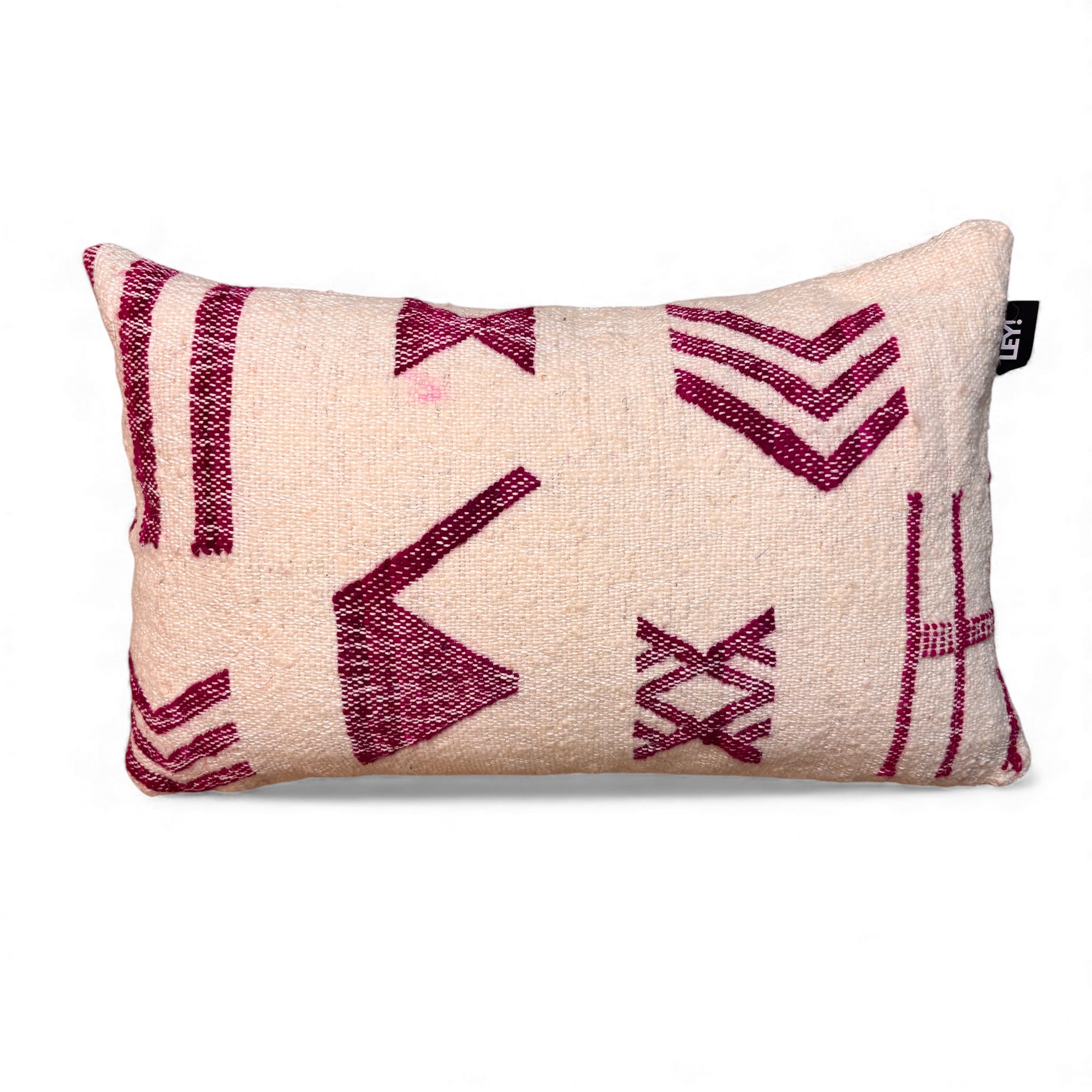 Das LEY! Kissen - Colorful Line - 30x50 von LEY! ist ein rechteckiges, cremefarbenes Kissen mit geometrischen, kastanienbraunen Mustern, wie Linien und X-Formen, und hat ein kleines schwarzes Etikett auf der rechten Seite.