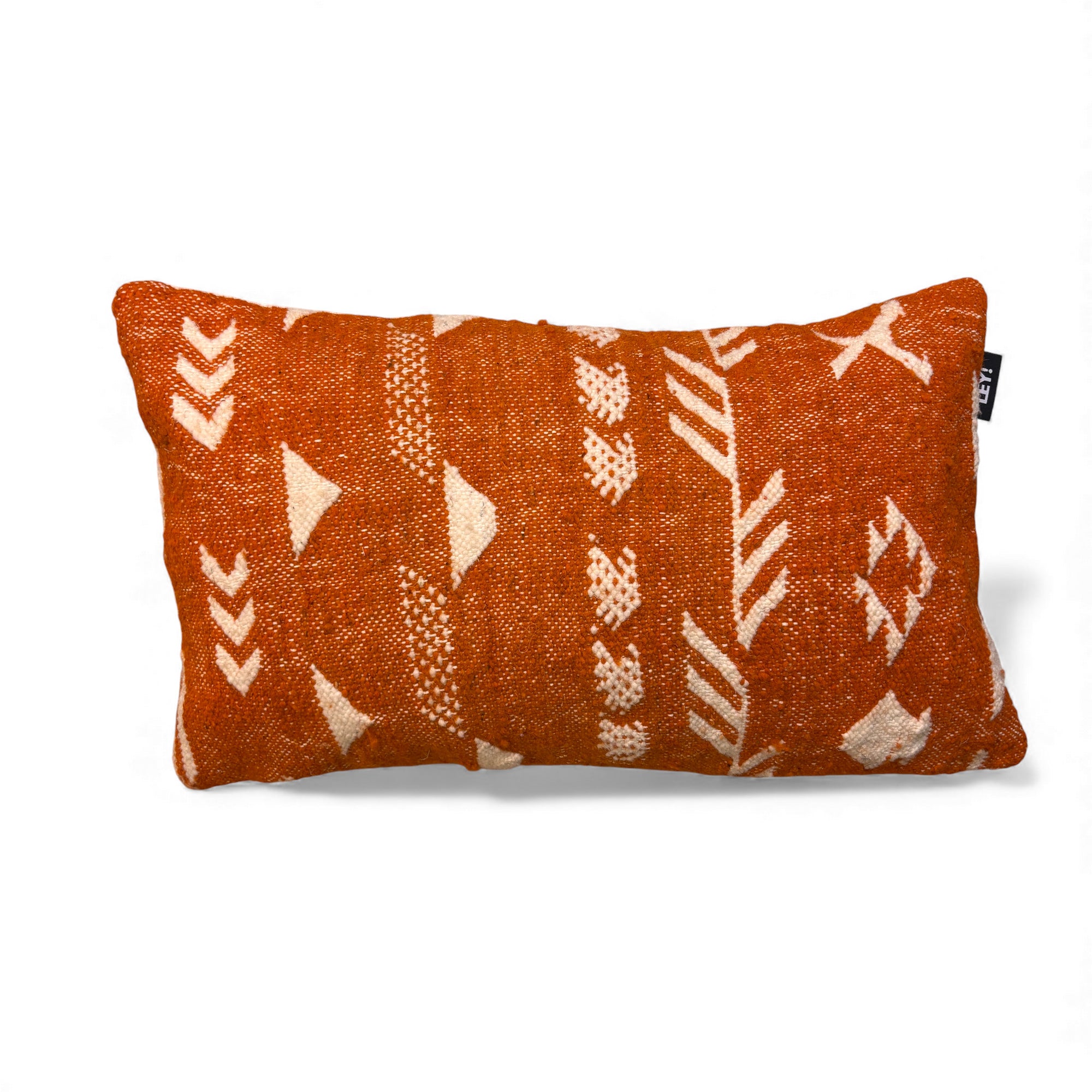 Das LEY! Kissen - Colorful Line - 30x50 ist ein rechteckiges, orangefarbenes Kissen mit strukturiertem Stoff und weißen, geometrischen Tribal-Mustern. Ein kleines schwarzes Etikett an der Seite kennzeichnet die Marke LEY! auf einem schlichten weißen Hintergrund.