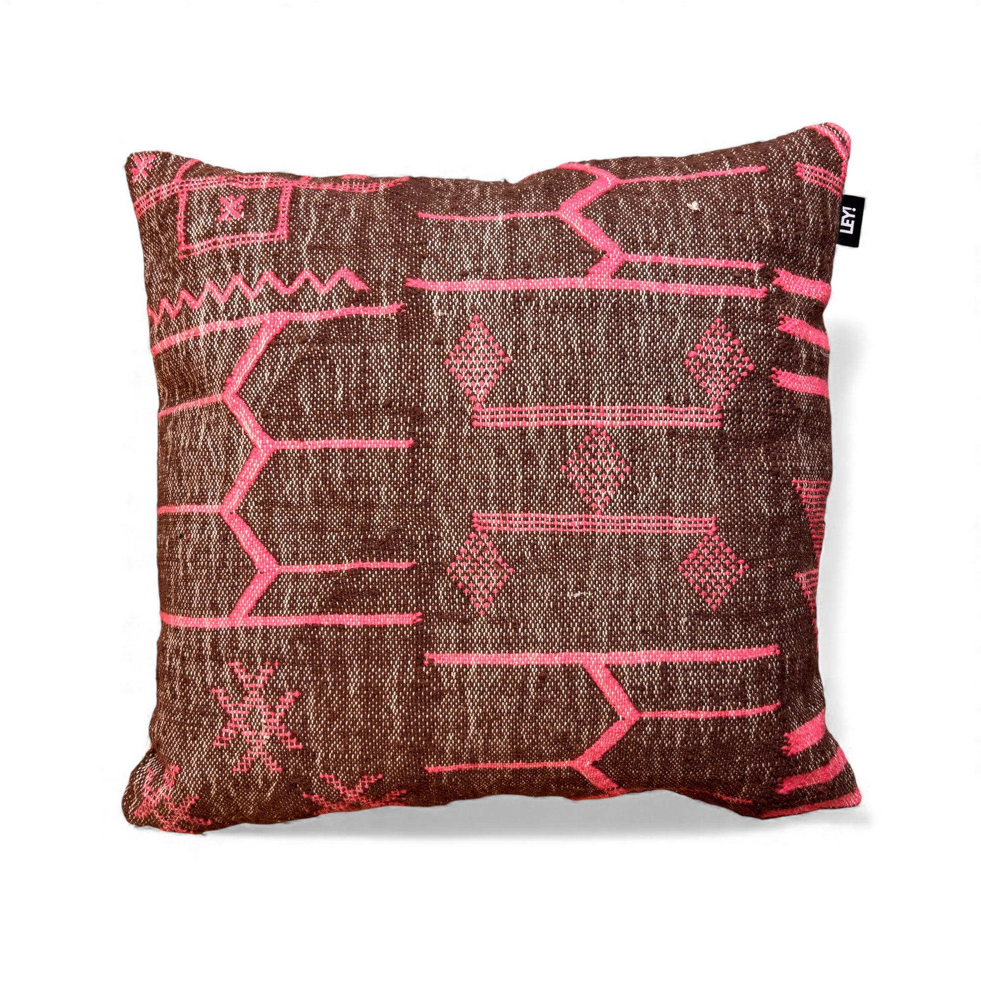 Das LEY! Kissen - Colorful Line - Fushia Edition 60x60 von LEY! ist ein quadratisches, braunes Kissen mit geometrischen, rosafarbenen Motiven, einem kleinen schwarzen Anhänger am oberen rechten Rand und einem schlichten weißen Hintergrund.
